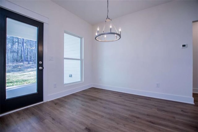 unfurnished dining area with dark wood-type flooring and a chandelier