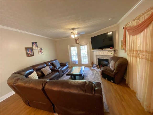 living room with hardwood / wood-style flooring, ceiling fan, a premium fireplace, a textured ceiling, and ornamental molding