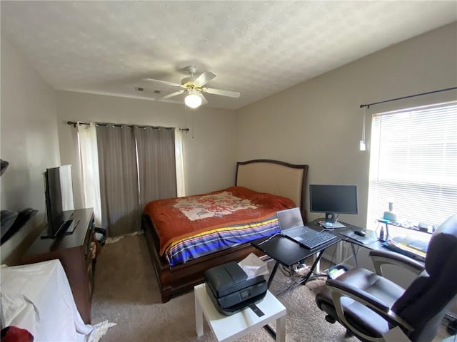 carpeted bedroom with ceiling fan and a textured ceiling