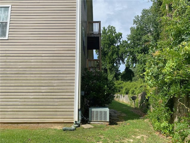 view of home's exterior with a balcony, cooling unit, and a lawn