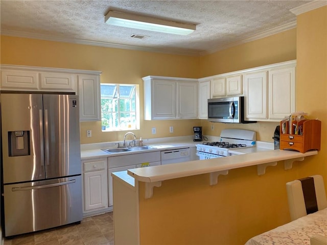 kitchen featuring a breakfast bar area, appliances with stainless steel finishes, a textured ceiling, white cabinets, and sink