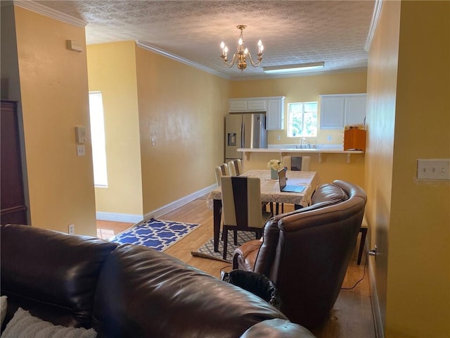 living room with light hardwood / wood-style floors, sink, an inviting chandelier, crown molding, and a textured ceiling