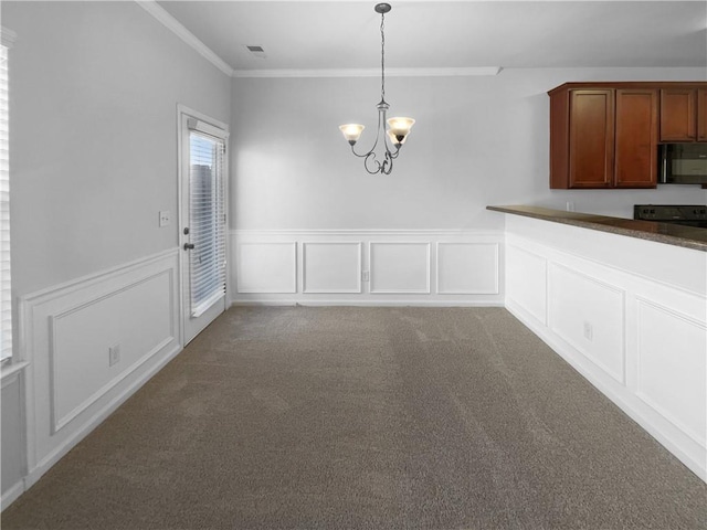 unfurnished dining area featuring a decorative wall, a notable chandelier, carpet flooring, visible vents, and ornamental molding
