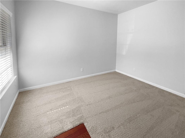 carpeted empty room featuring baseboards