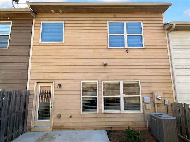 rear view of house with cooling unit, a patio area, and fence