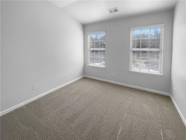 unfurnished room featuring carpet flooring, visible vents, and baseboards