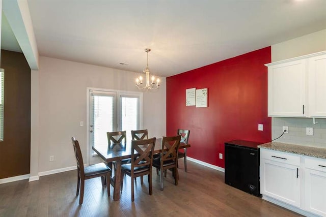 dining room with a chandelier, dark wood-type flooring, and baseboards