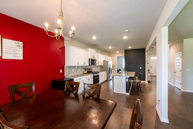 dining space featuring a chandelier, baseboards, dark wood finished floors, an accent wall, and recessed lighting