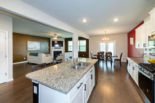 kitchen featuring a sink, stainless steel appliances, a chandelier, dark wood finished floors, and a fireplace