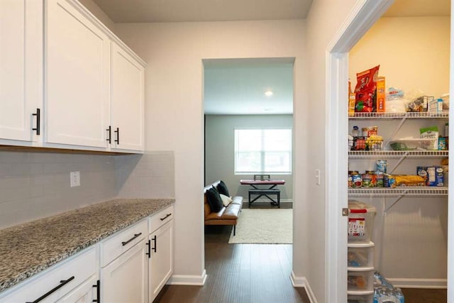 bar area with decorative backsplash, dark wood-style flooring, and baseboards