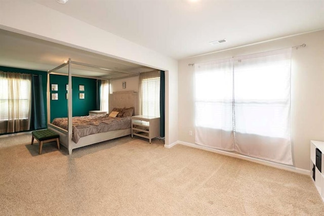 bedroom with light colored carpet and multiple windows