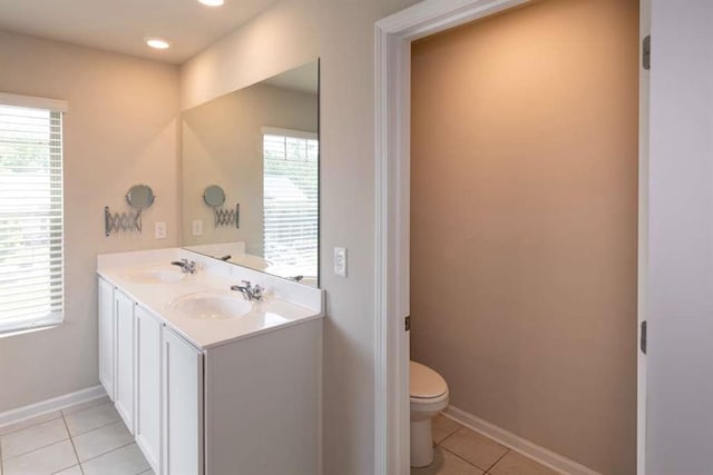 bathroom with tile patterned flooring, toilet, double vanity, and baseboards