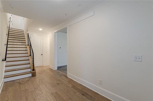 foyer entrance with ornamental molding and light wood-type flooring