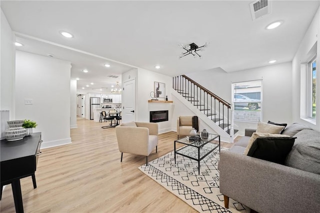 living room with light hardwood / wood-style flooring and a notable chandelier