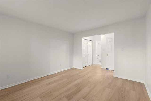 empty room featuring baseboards and light wood-style flooring