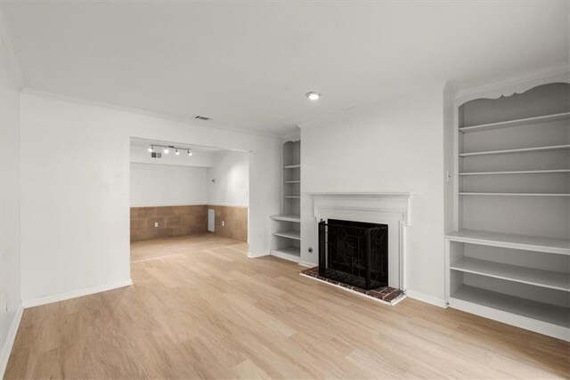 unfurnished living room with hardwood / wood-style flooring, ornamental molding, and built in shelves