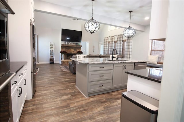 223 Deans Dr, Dawsonville, GA 30534 - kitchen with open floor plan, a sink, dark wood-style floors, a stone fireplace, and appliances with stainless steel finishes