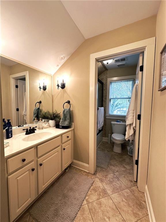 bathroom with tile patterned flooring, vanity, vaulted ceiling, and toilet