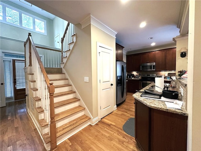 kitchen featuring light wood-type flooring, appliances with stainless steel finishes, and dark brown cabinetry