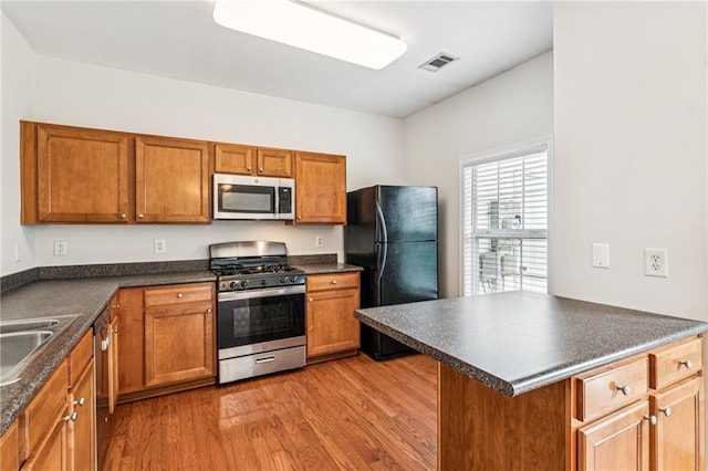 1049 Prestwyck Ct, Alpharetta, GA 30004 - kitchen featuring stainless steel appliances, dark countertops, wood finished floors, and brown cabinets