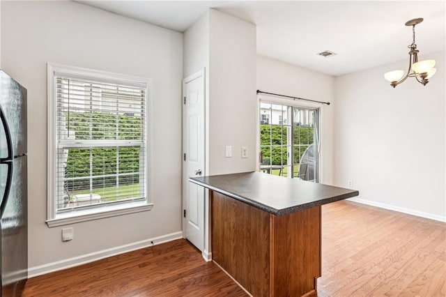 1049 Prestwyck Ct, Alpharetta, GA 30004 - kitchen with a peninsula, freestanding refrigerator, wood finished floors, dark countertops, and a chandelier