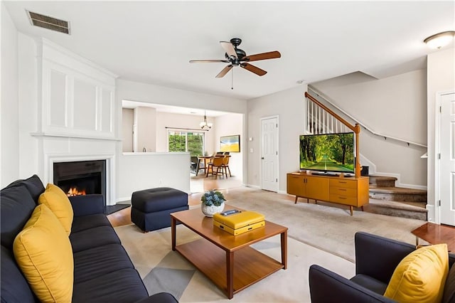 1049 Prestwyck Ct, Alpharetta, GA 30004 - living room featuring a ceiling fan, stairs, a warm lit fireplace, and a chandelier