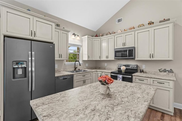 417 Beamer Rd SW, Calhoun, GA 30701 - kitchen featuring stainless steel appliances, a sink, vaulted ceiling, dark wood-type flooring, and a center island
