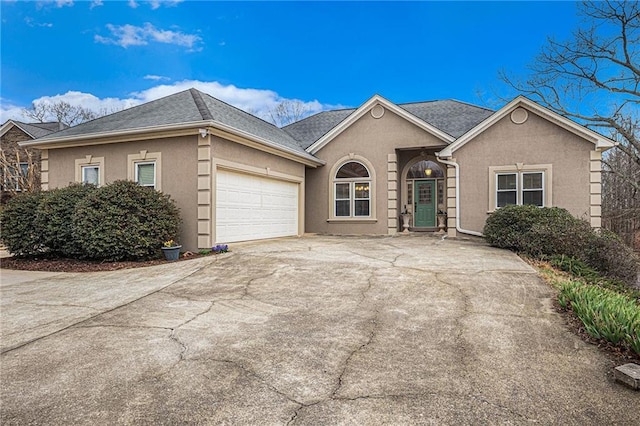 ranch-style house featuring a garage, driveway, and stucco siding