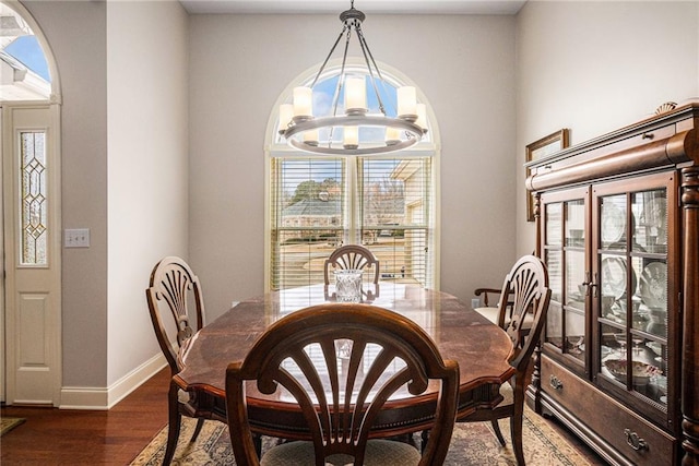 dining room with a notable chandelier, dark wood-style floors, and baseboards