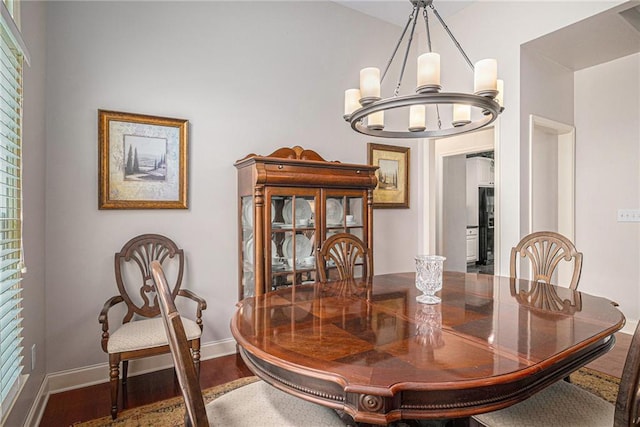 dining room with a chandelier, baseboards, and wood finished floors