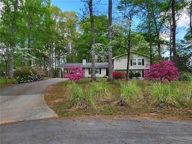 4561 N Woodlake Ln SE, Conyers, GA 30013 - split level home featuring concrete driveway, a chimney, and a carport