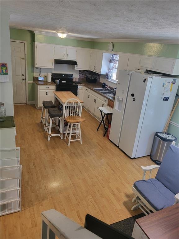4561 N Woodlake Ln SE, Conyers, GA 30013 - kitchen with a textured ceiling, white cabinets, white refrigerator with ice dispenser, and black range with electric stovetop