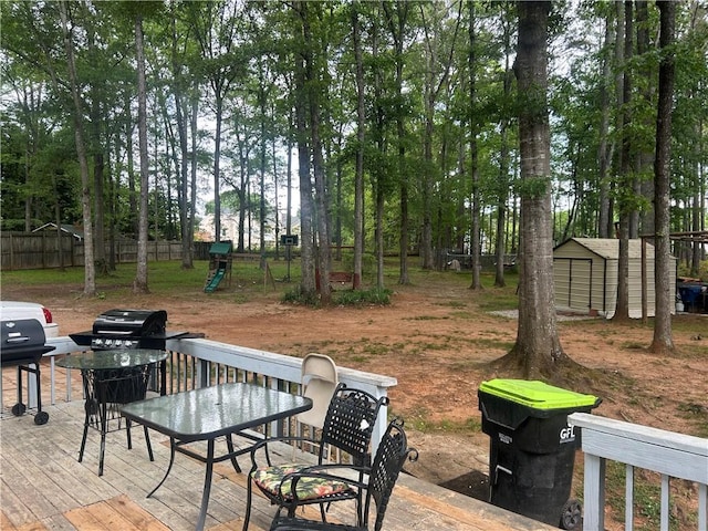 4561 N Woodlake Ln SE, Conyers, GA 30013 - wooden terrace featuring a storage shed, an outbuilding, fence, a playground, and outdoor dining space