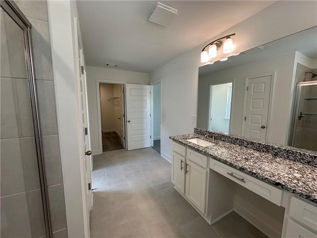 bathroom with visible vents, vanity, baseboards, a spacious closet, and a stall shower