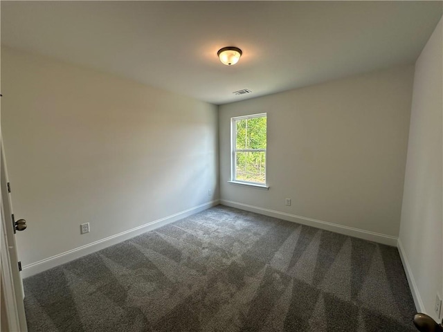 unfurnished room featuring baseboards, dark colored carpet, and visible vents
