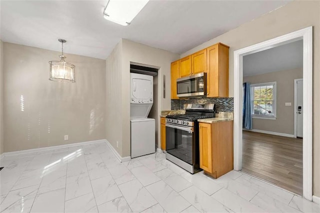 kitchen with stainless steel appliances, stacked washer and dryer, pendant lighting, light hardwood / wood-style floors, and decorative backsplash