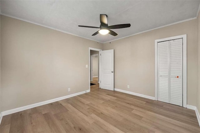 unfurnished bedroom with ceiling fan, light wood-type flooring, crown molding, and a closet