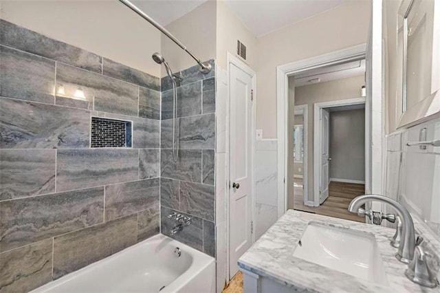 bathroom with vanity, wood-type flooring, and tiled shower / bath