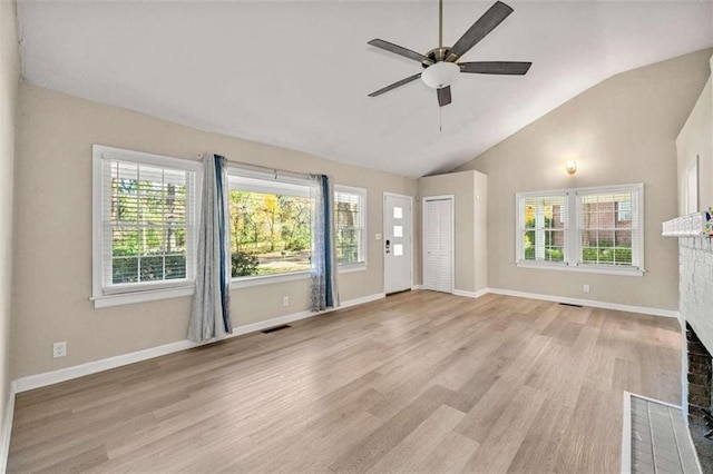 unfurnished living room with a fireplace, light wood-type flooring, vaulted ceiling, and plenty of natural light