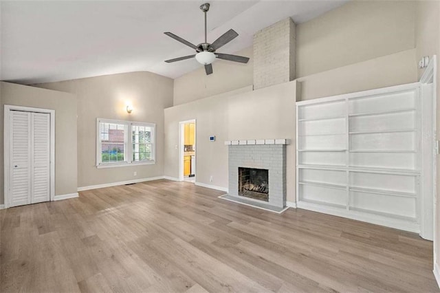 unfurnished living room featuring ceiling fan, a fireplace, light hardwood / wood-style floors, and vaulted ceiling