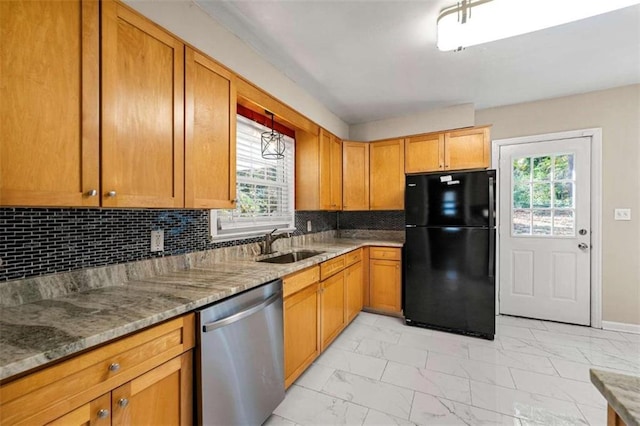 kitchen featuring tasteful backsplash, black refrigerator, stainless steel dishwasher, and sink