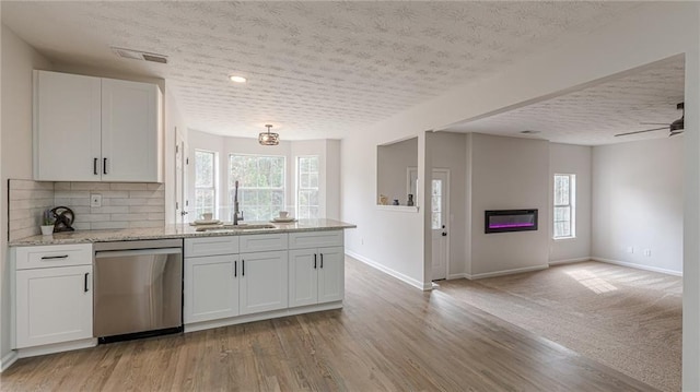 kitchen featuring a peninsula, a sink, visible vents, open floor plan, and stainless steel dishwasher