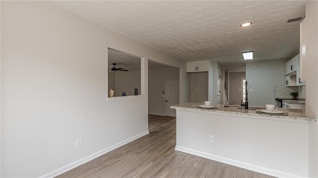 kitchen featuring a textured ceiling, electric range, a sink, baseboards, and light wood-style floors