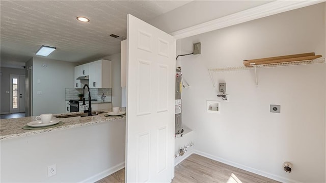 clothes washing area with baseboards, visible vents, hookup for a washing machine, hookup for an electric dryer, and light wood-type flooring