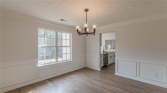 unfurnished dining area with dark wood-type flooring, visible vents, a sink, and a textured ceiling