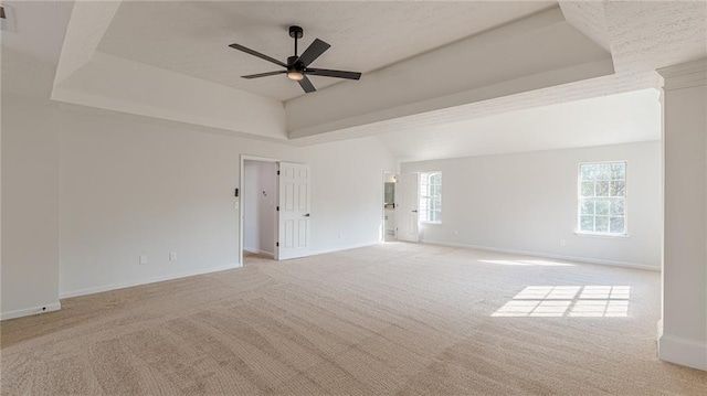 carpeted empty room featuring ceiling fan, a tray ceiling, and baseboards