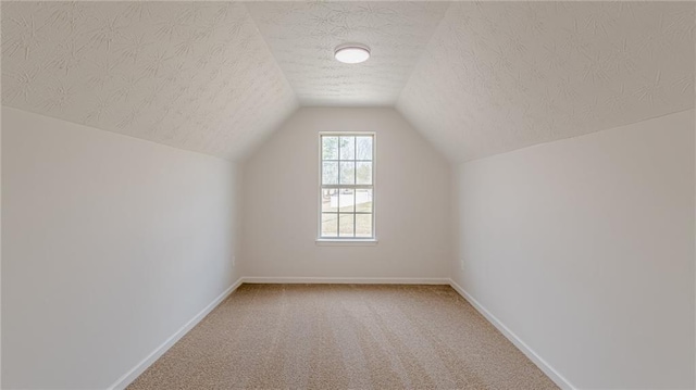 bonus room featuring lofted ceiling, carpet flooring, a textured ceiling, and baseboards