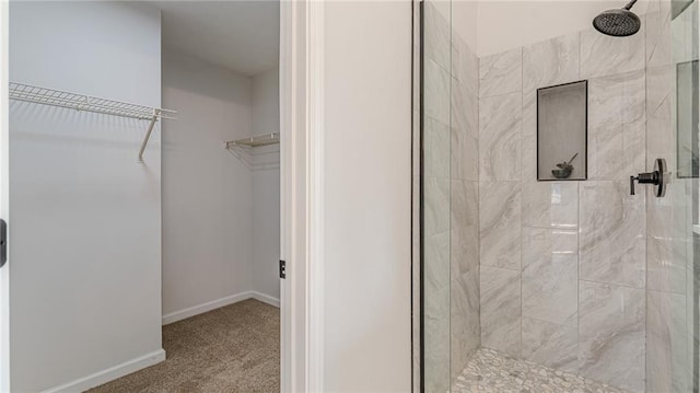 full bathroom with a shower stall, a walk in closet, and baseboards