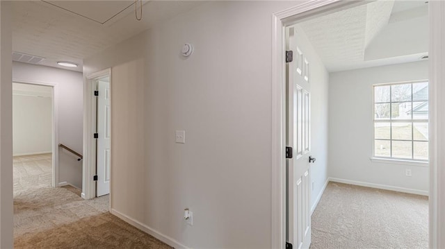 corridor featuring carpet floors, baseboards, visible vents, and an upstairs landing