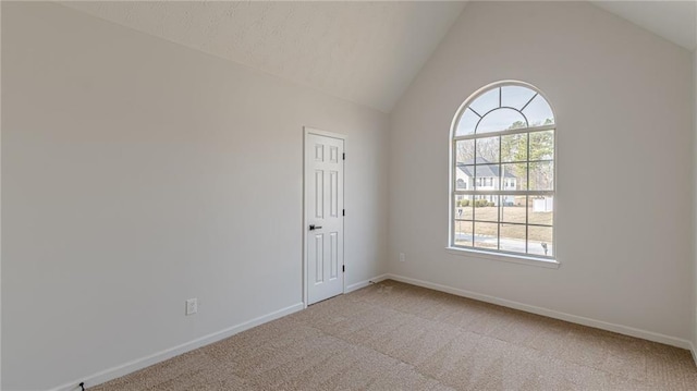 spare room with light carpet, baseboards, and lofted ceiling